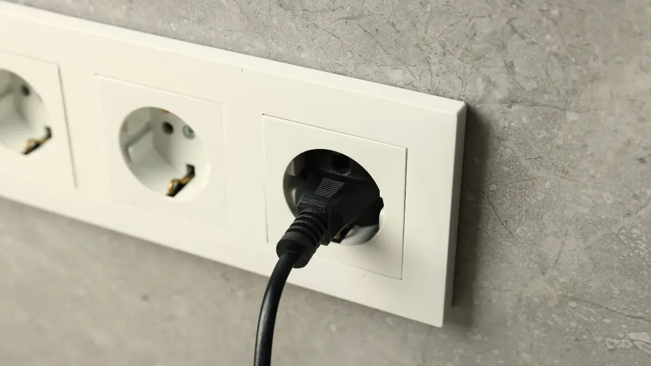 Jordet stikkontakt montert på vegg i moderne bolig med elektrisk apparat tilkoblet.